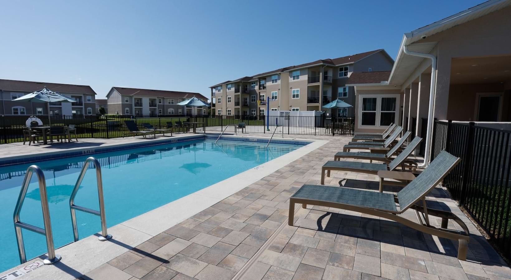A sparkling blue resort-style pool at Heritage Key Villas surrounded by lounge chairs and modern apartment buildings.