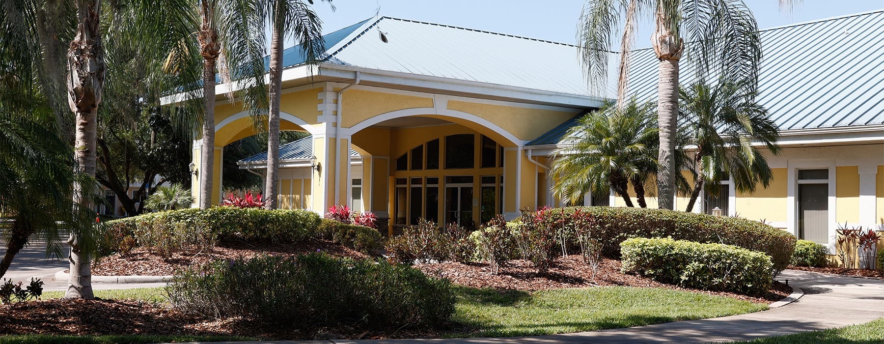 Clubhouse entrance and lush tropical landscaping at Heritage Key Villas apartments for rent in Kissimmee, FL