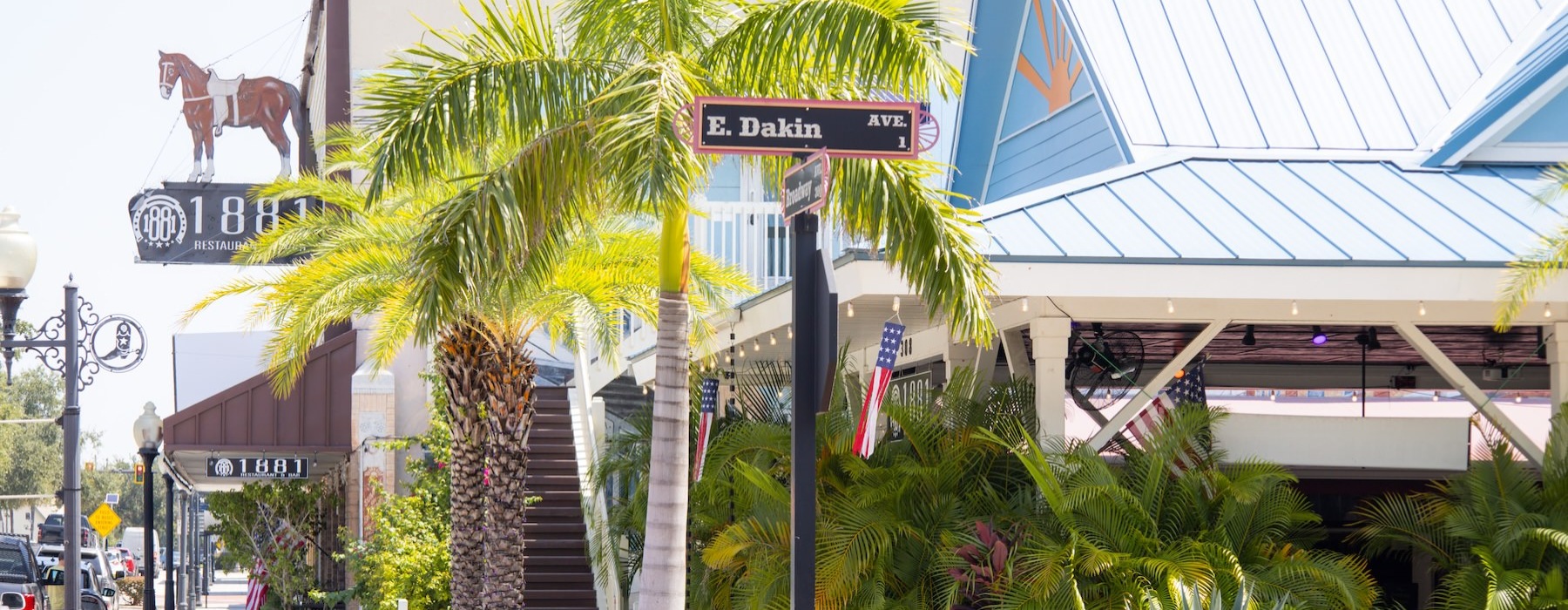 a street sign next to a palm tree and a building